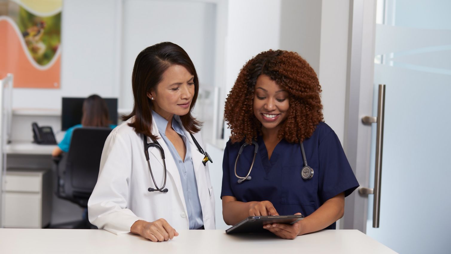 Two doctors in white lab coats discuss information on a chart.