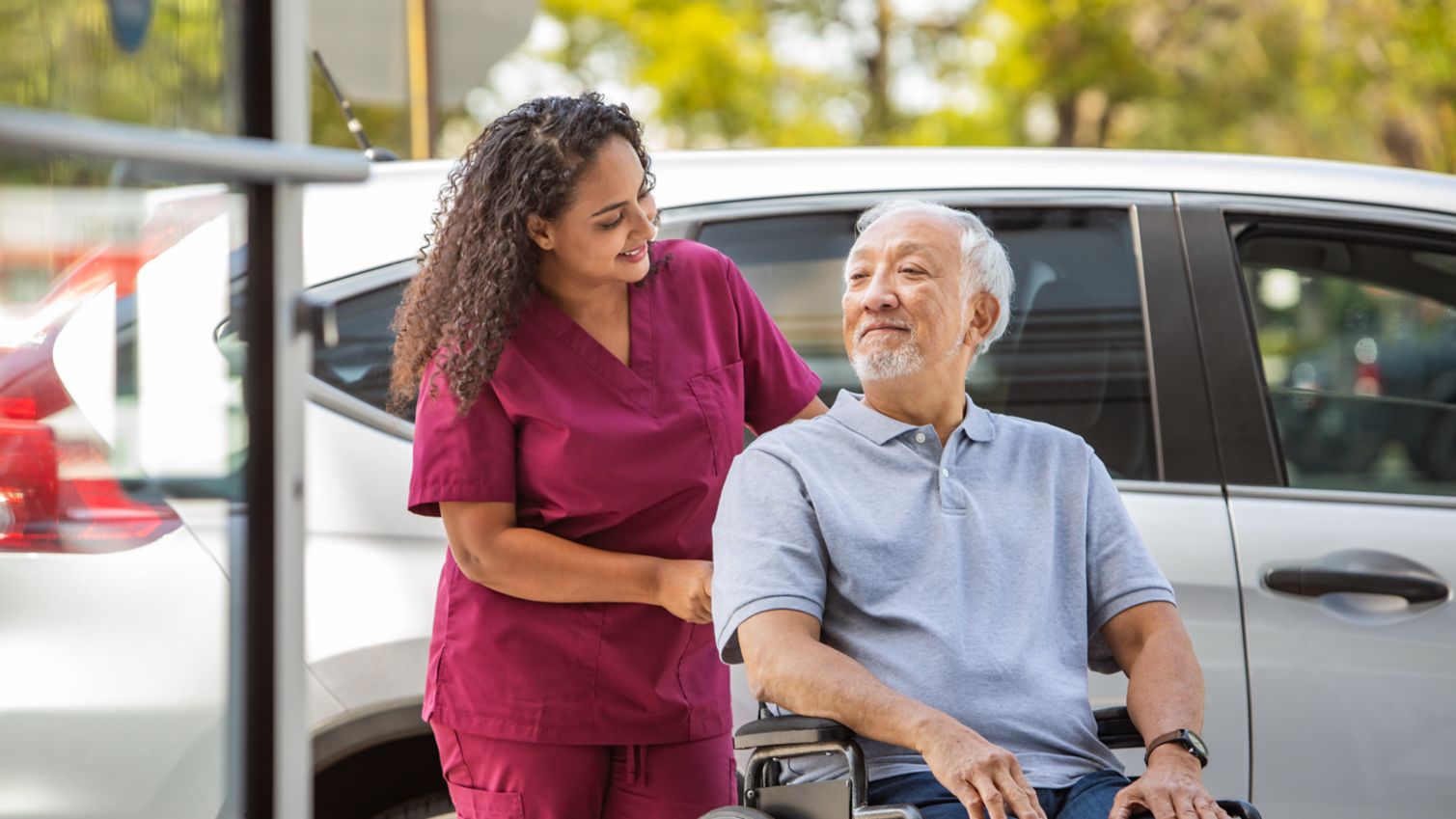 A nurse pushes an elderly man's wheelchair