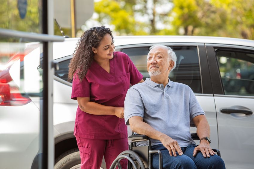 A man in a wheelchair is pushed by his caregiver. 