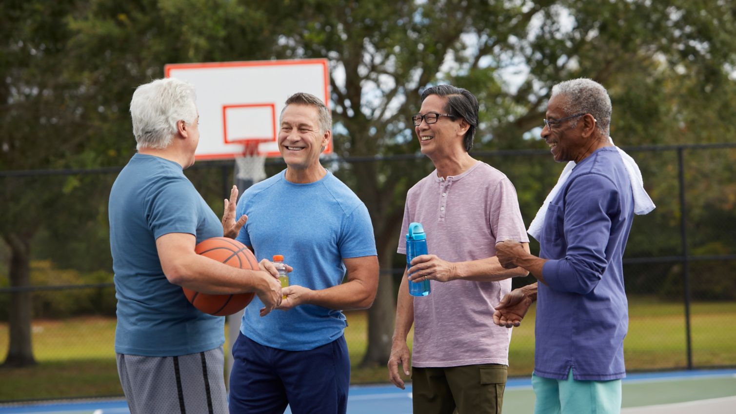 A group of friends chat on a basketball court.