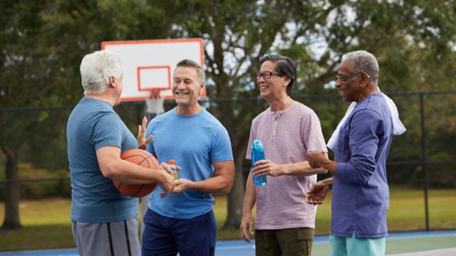A group of friends chat on a basketball court.