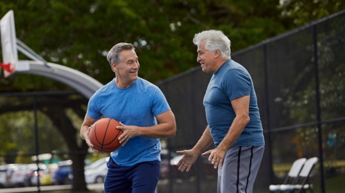 Two men smile while playing basketball. 