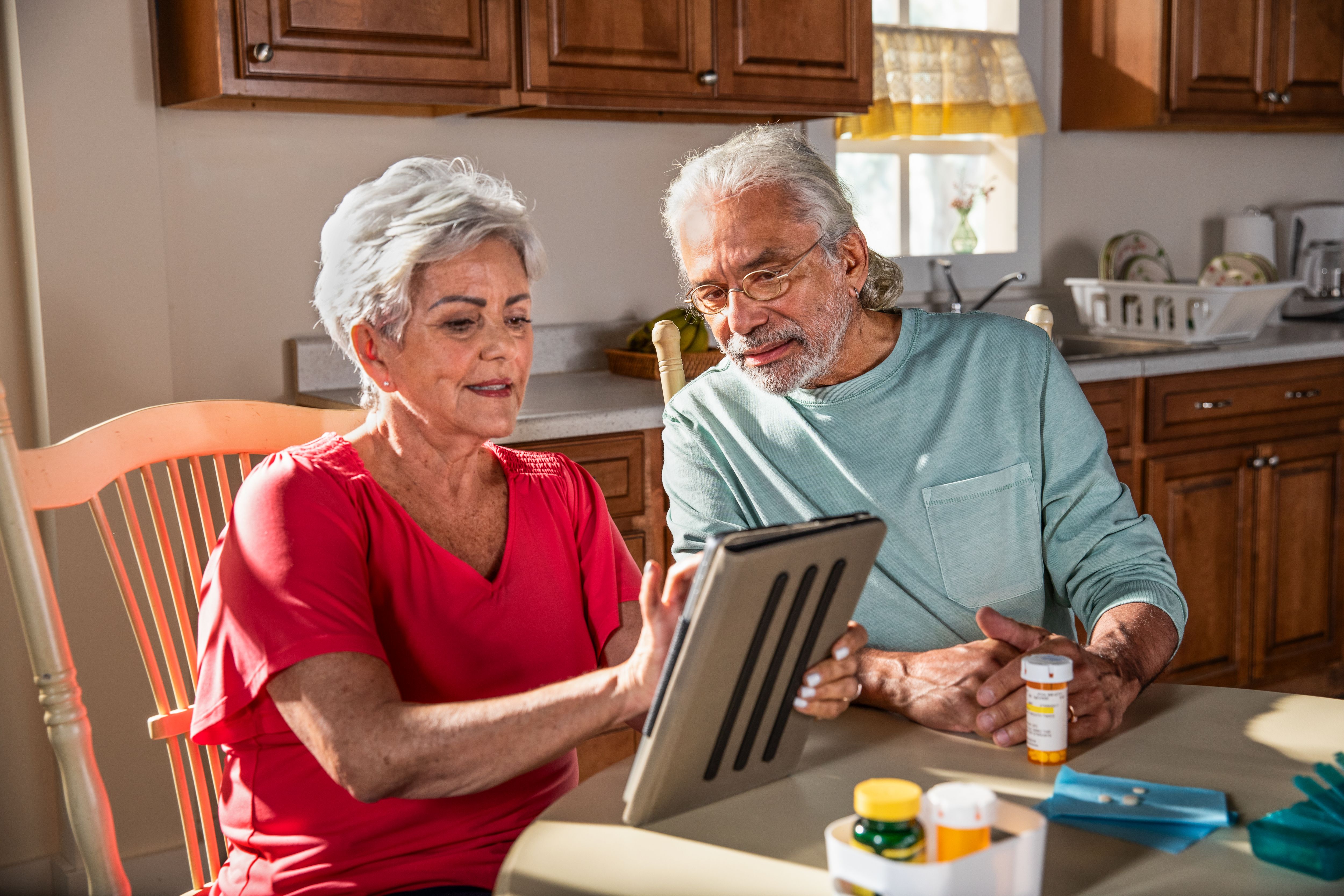 A couple looks at a tablet in their kitchen.