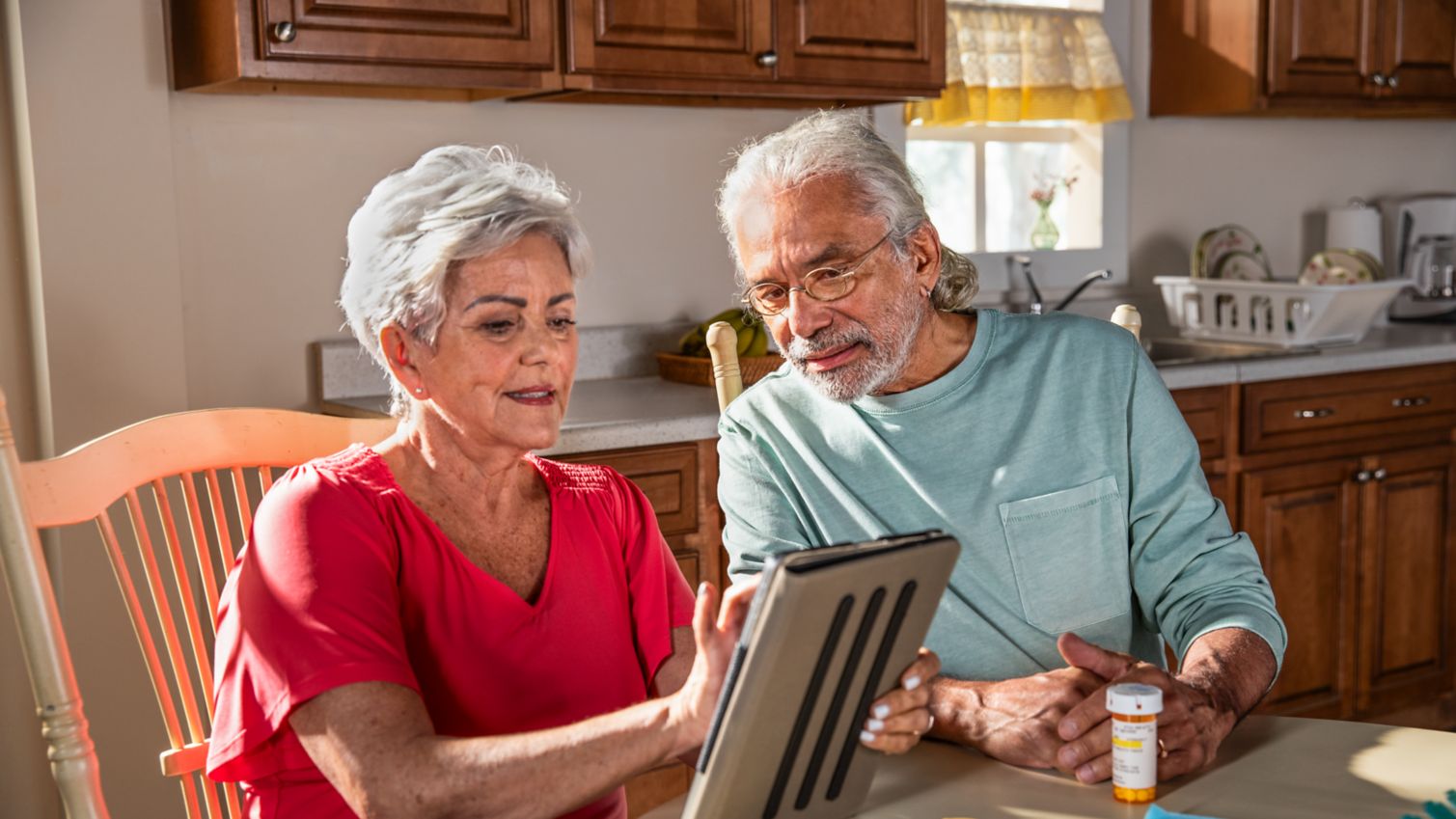 A couple looks at a tablet in their kitchen.
