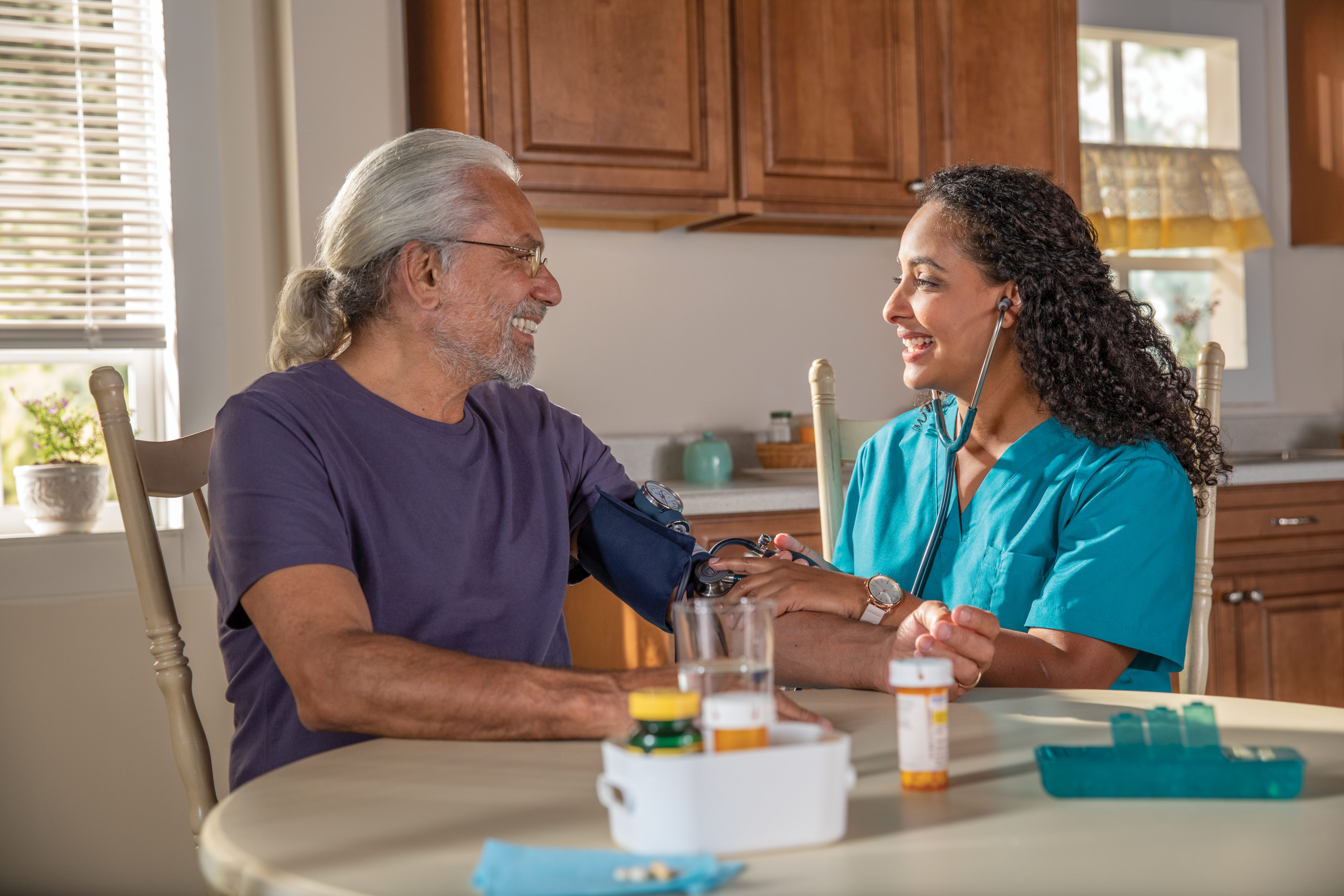 Senior man reviews using blood sugar kit with nurse at home at the table