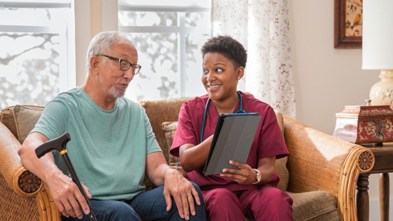 Older man sitting on couch talking with home health nurse