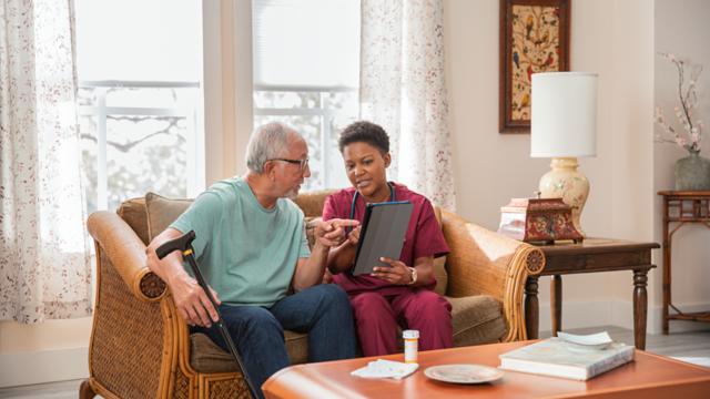 A man meets with his caregiver in his living room.