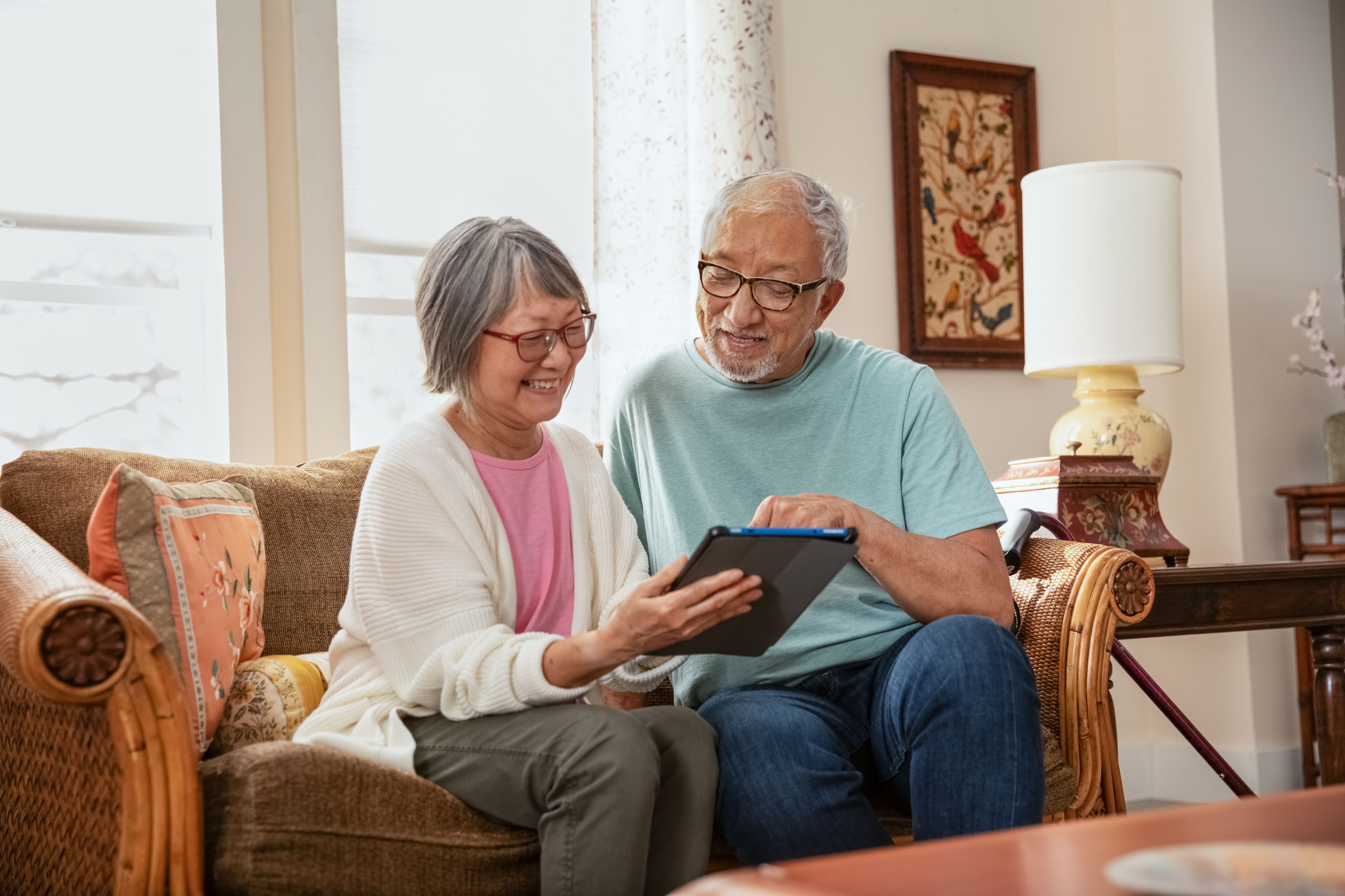 Senior couple sitting together on couch looking at tablet