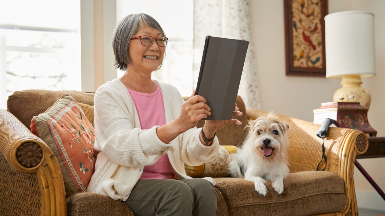 A woman uses a tablet to make a video call from her sofa. 