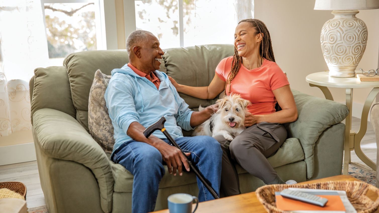 A man laughs on his sofa with his adult daughter. 