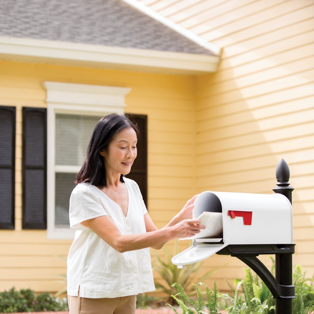 A woman pulls a package out of her mailbox. 