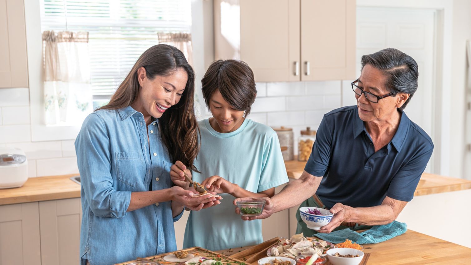 A man makes dumplings with his daughter and grandson. 