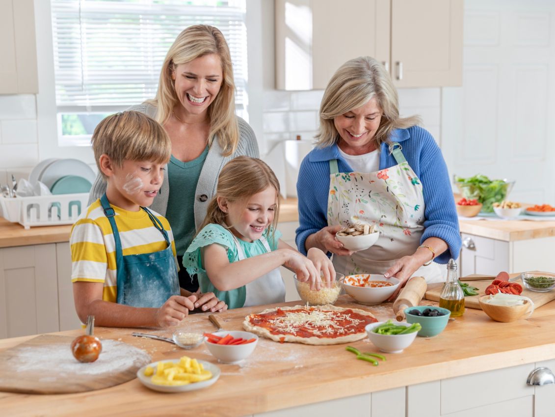 Family making a pizza in the kitchen.