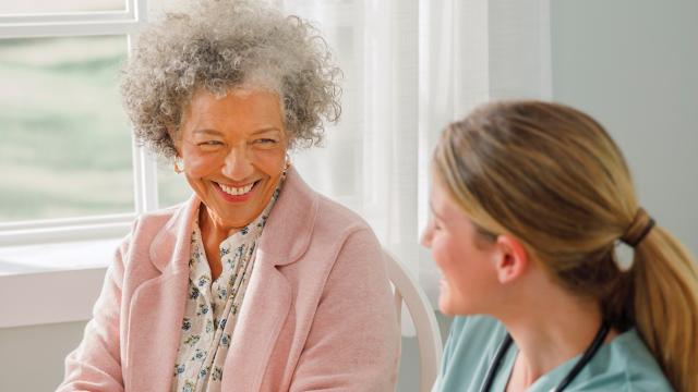 A caregiver reassures a woman at her kitchen table. 