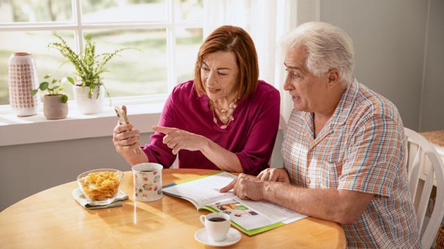 A couple looks over plan options over coffee in their kitchen.