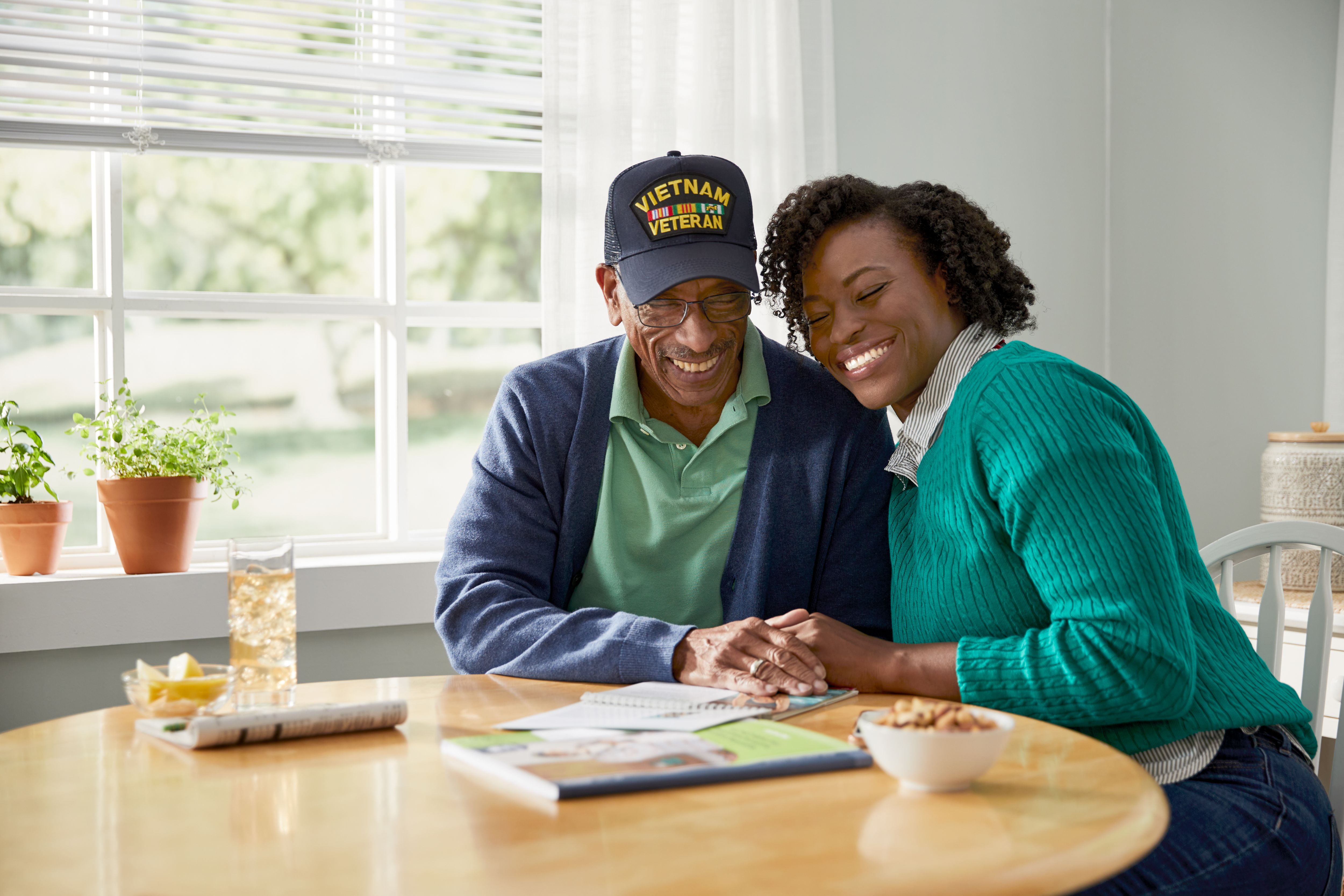 Senior man sitting at table with adult daughter and reading enrollment booklet