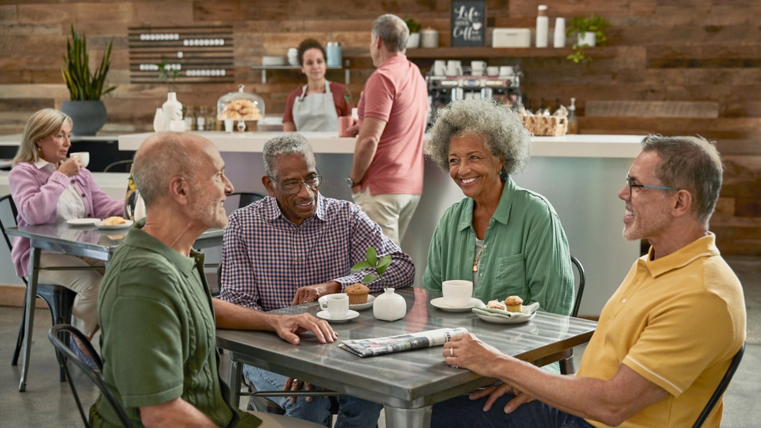 A group of friends chat at a table in a coffee shop.
