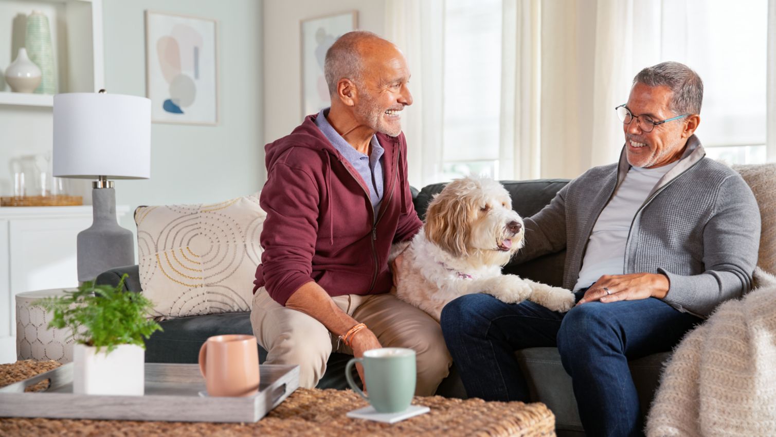 A couple and their dog sit close on their sofa.