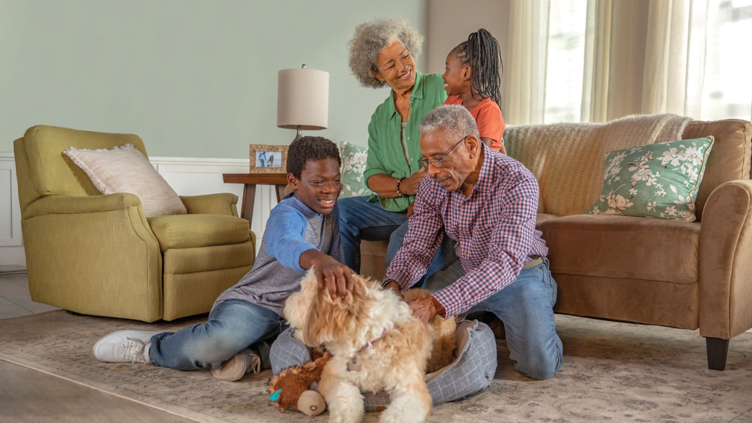 A couple and their grandchildren spend time together at home with their dog. 