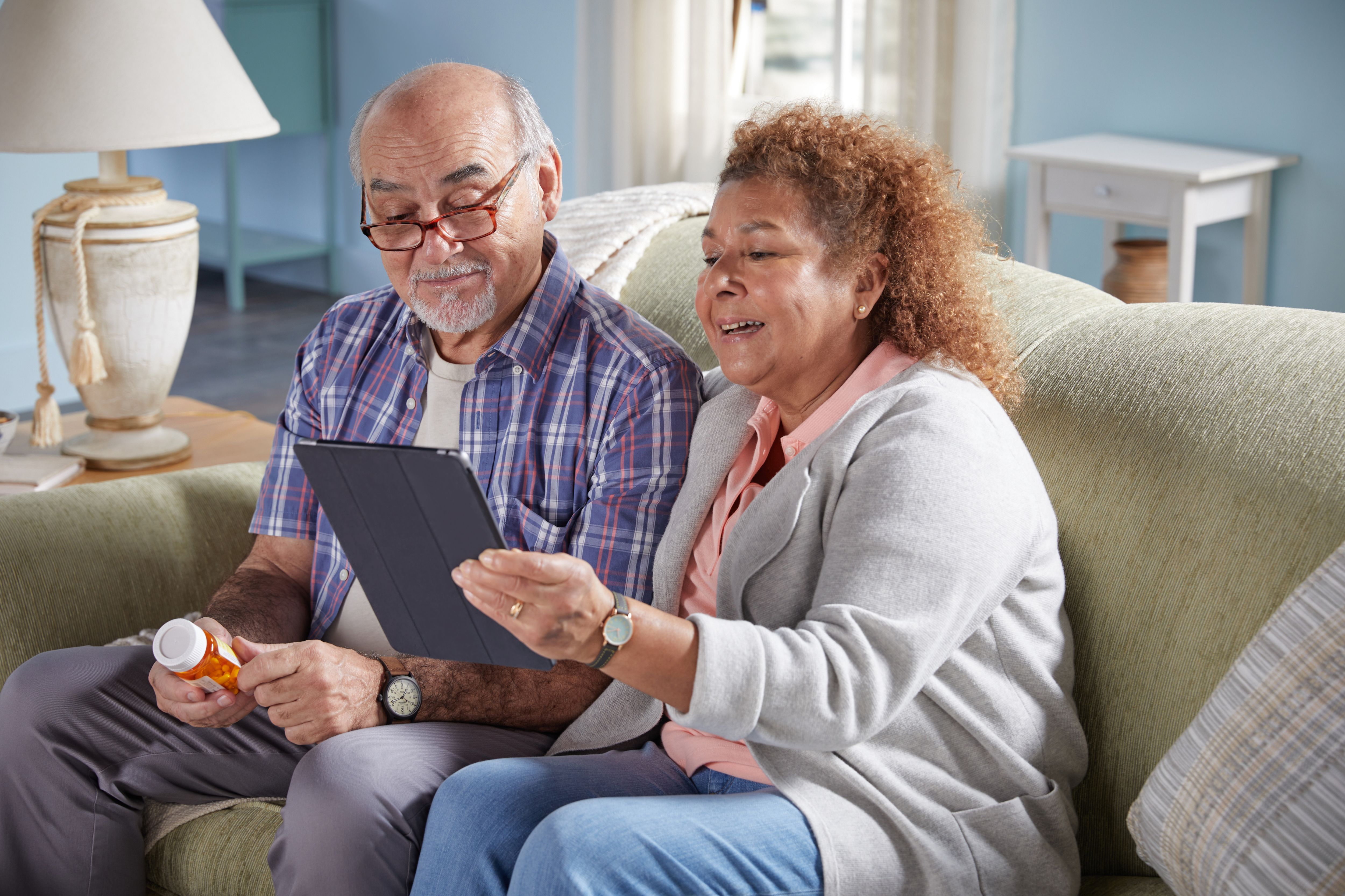Senior couple sitting on couch in living room reviewing medications