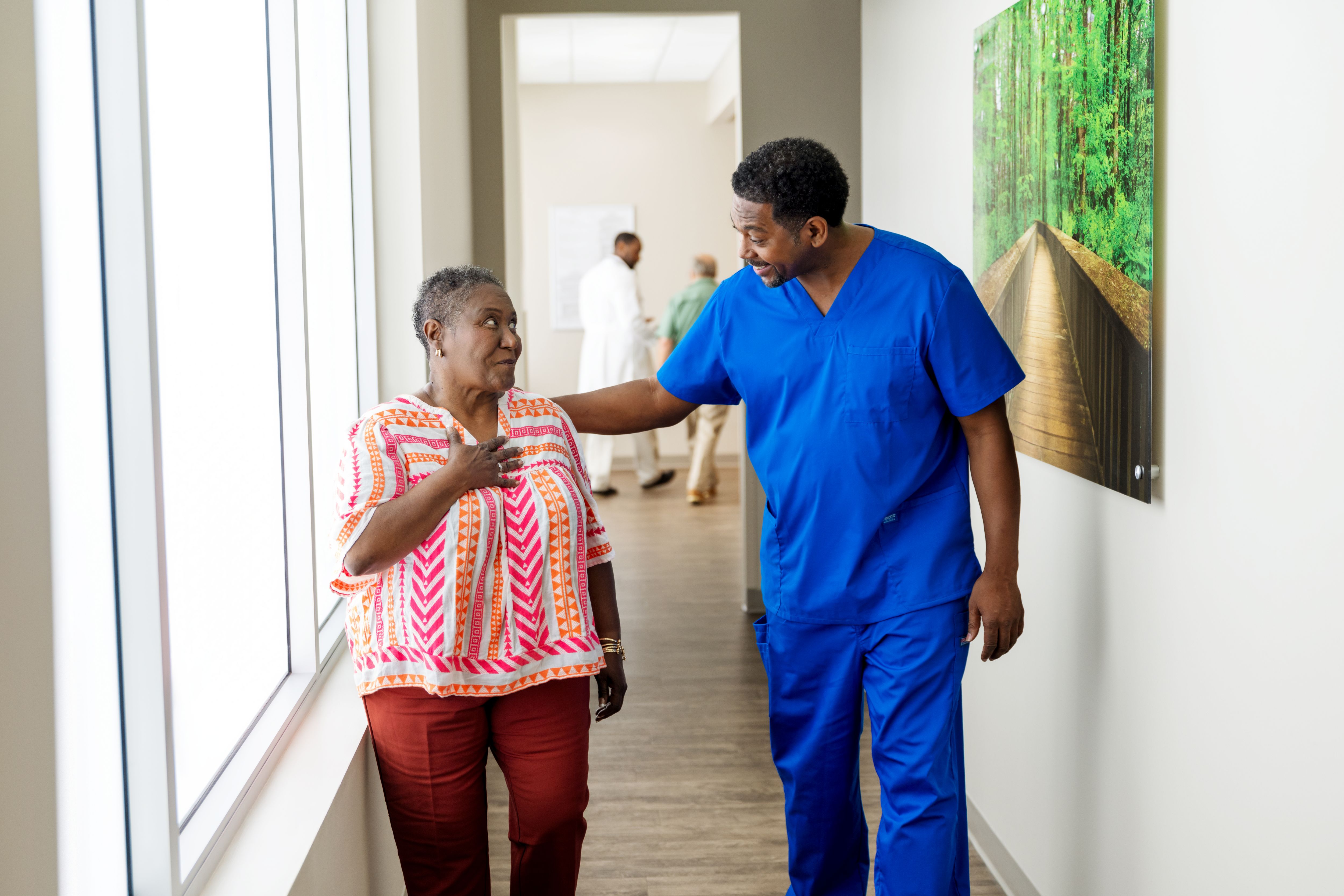 Senior woman talking with a nurse in a clinic hallway