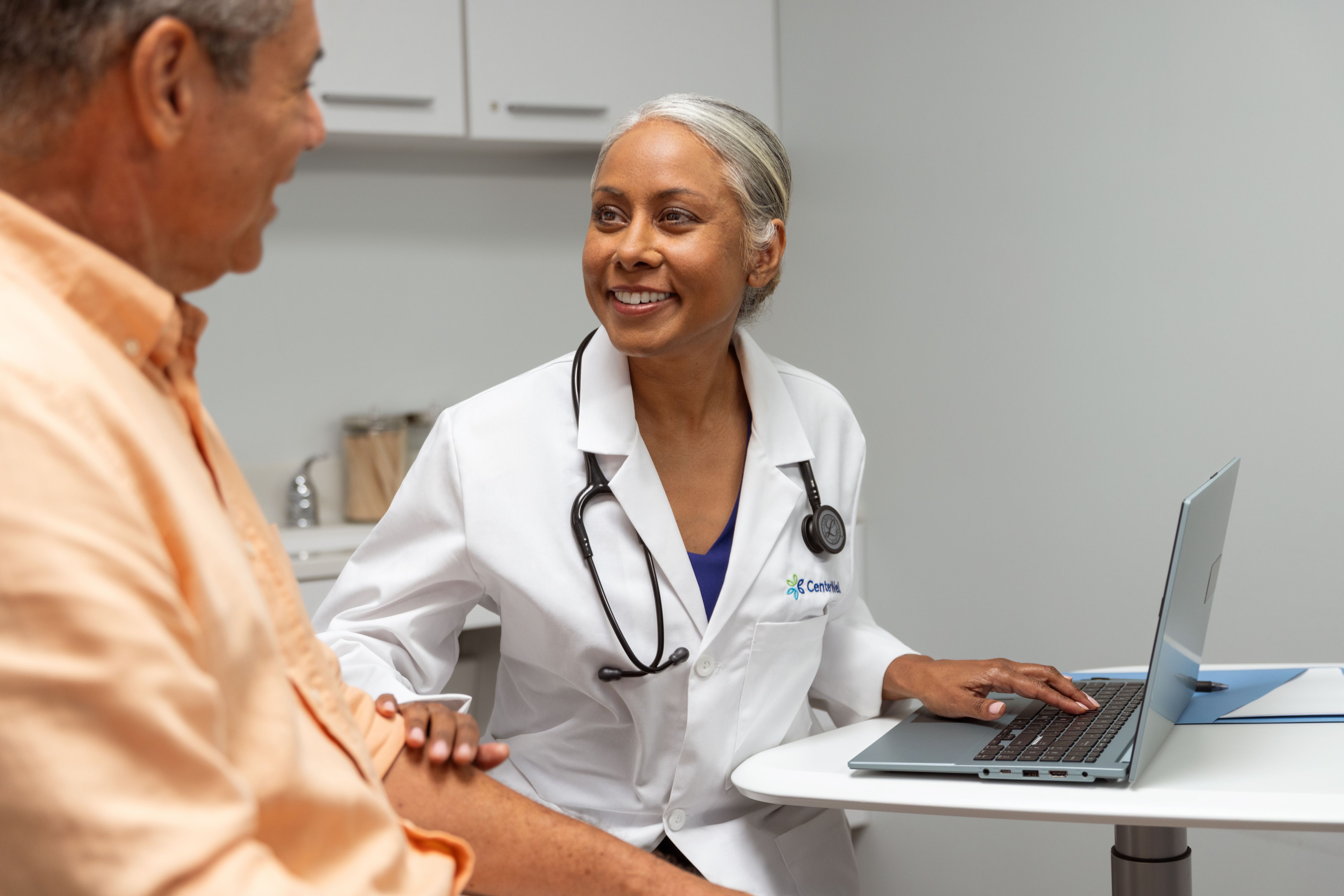 Black female doctor with hispanic male patient in doctors office
