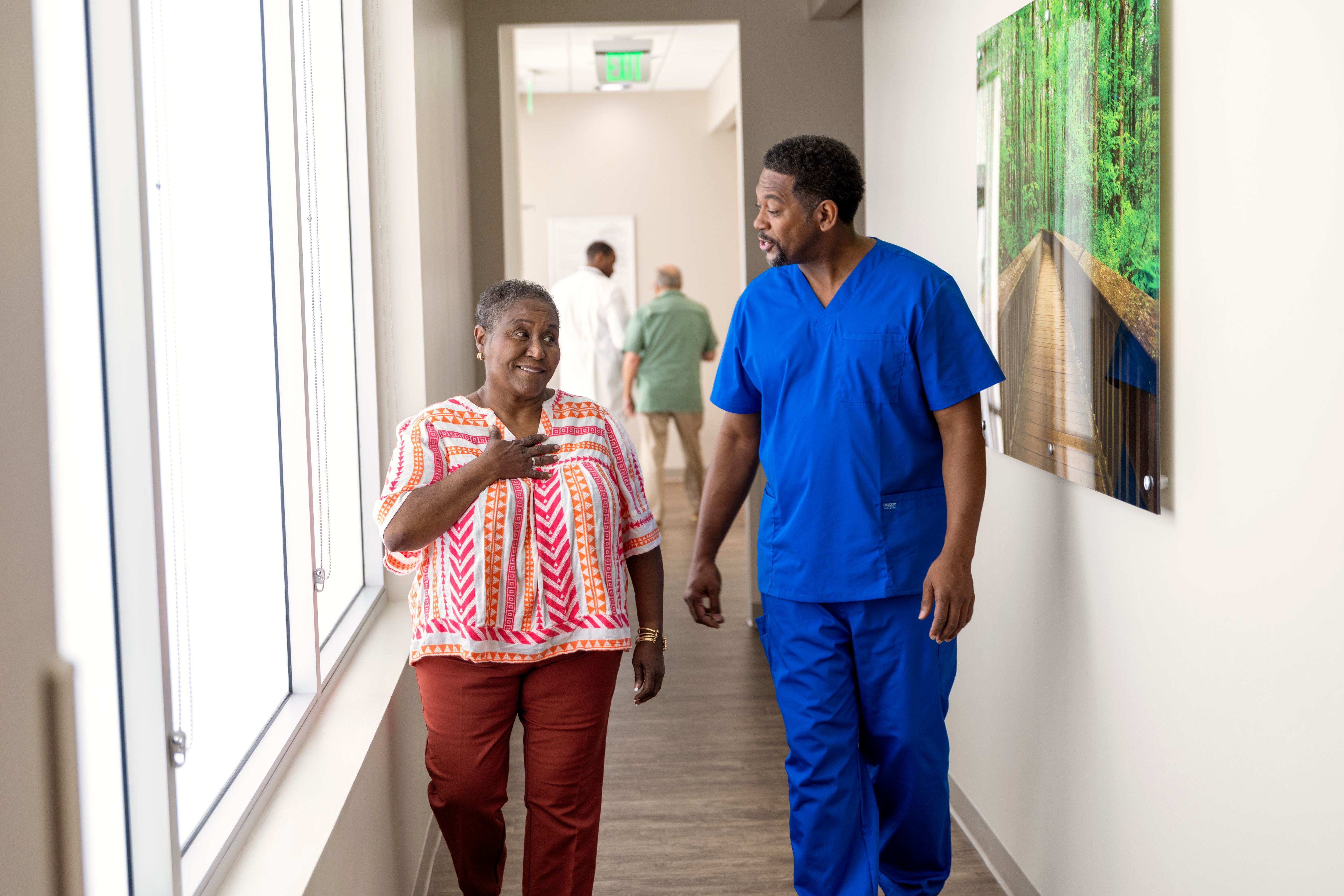 Black woman and male nurse walking down hall