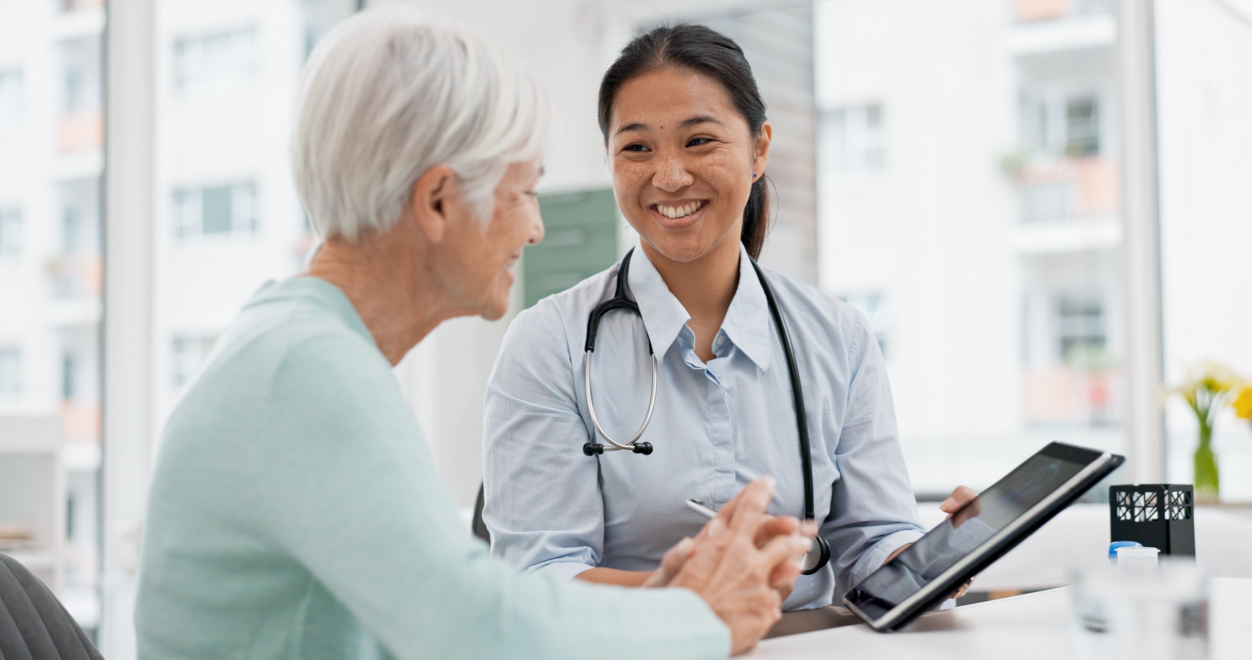 Talking, doctor or elderly patient with tablet for results, digital report or health report history online in hospital. Medical, healthcare or nurse with advice, news update or support for old woman.