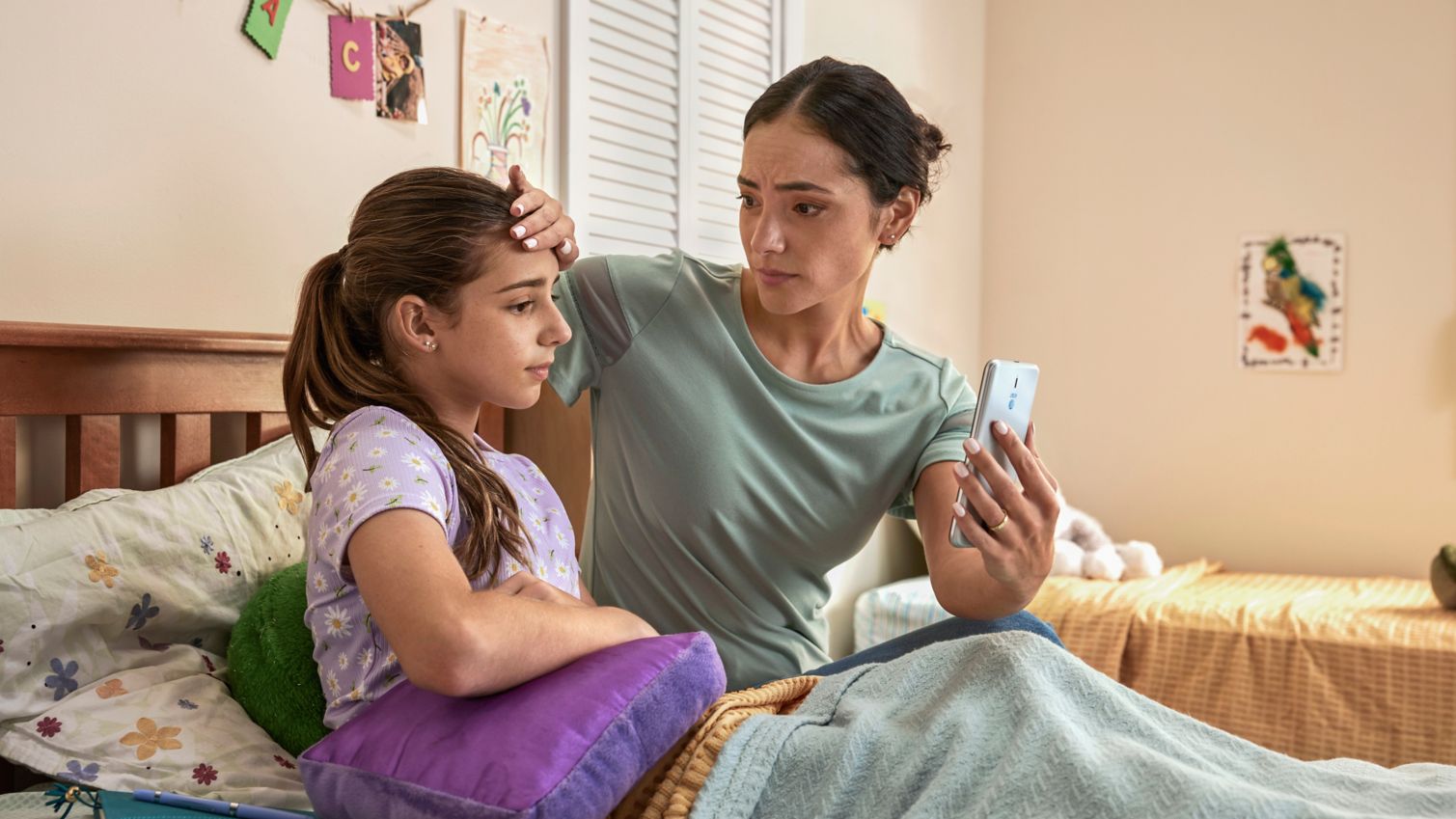 Woman showing phone to daughter with concerned look