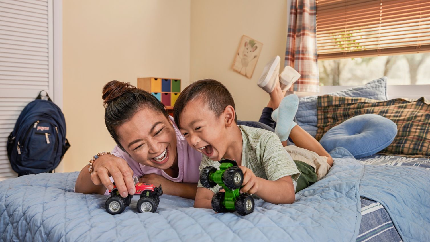 Adult and child playing with trucks in child’s bedroom.