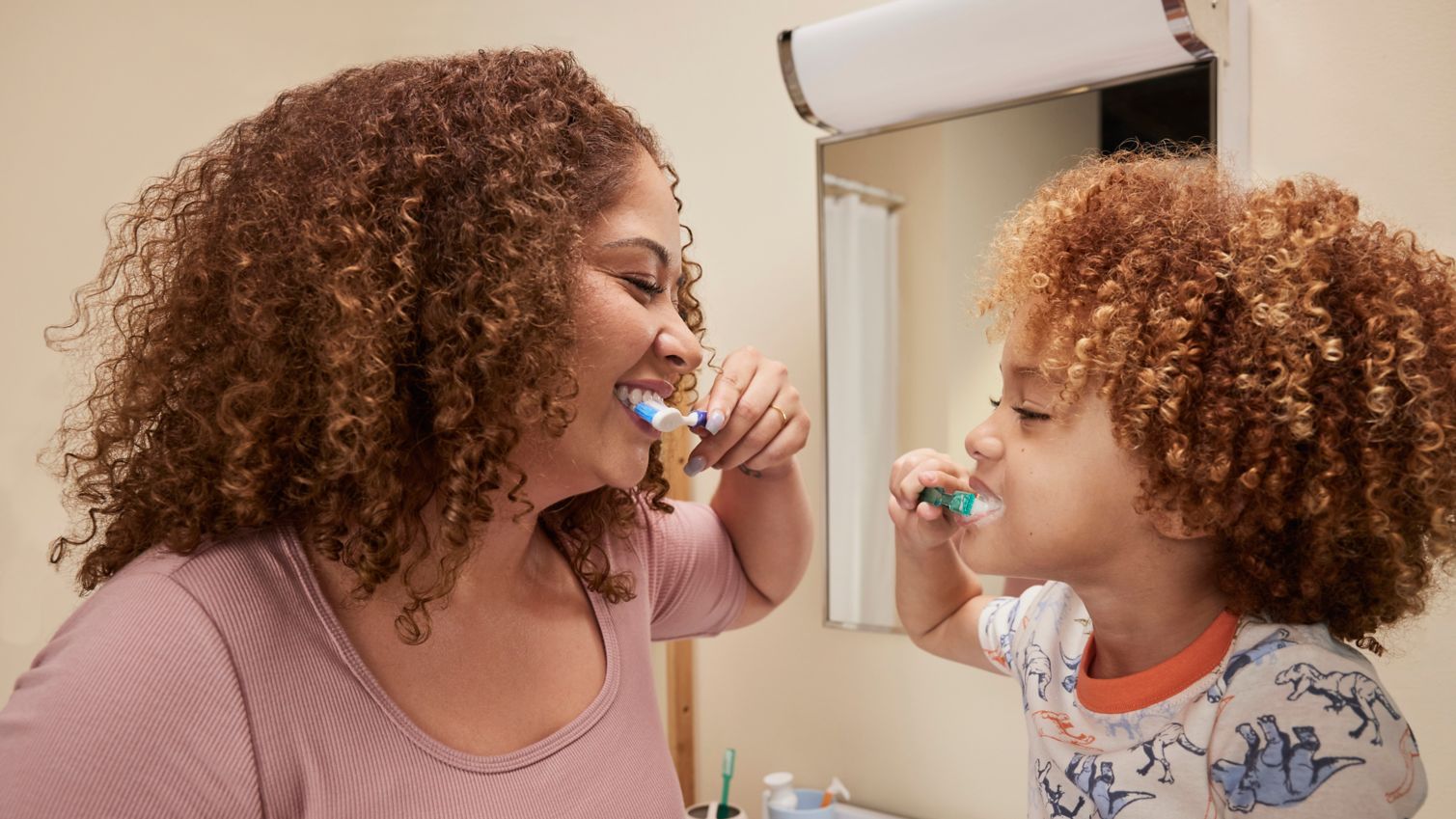 Adult and child brushing their teeth together in the bathroom