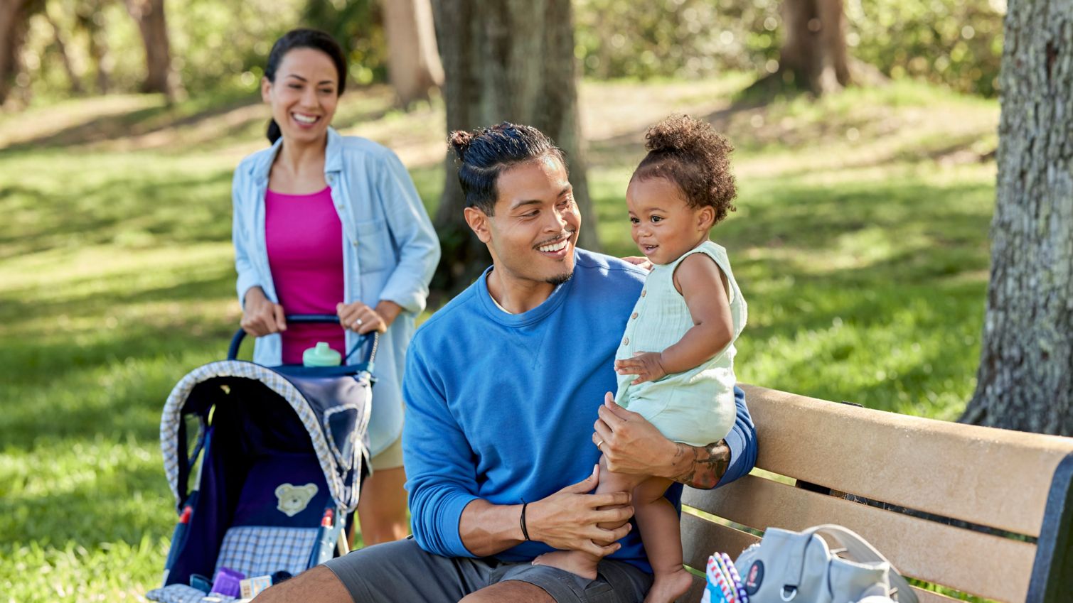 Two adults at a park bench with a toddler.