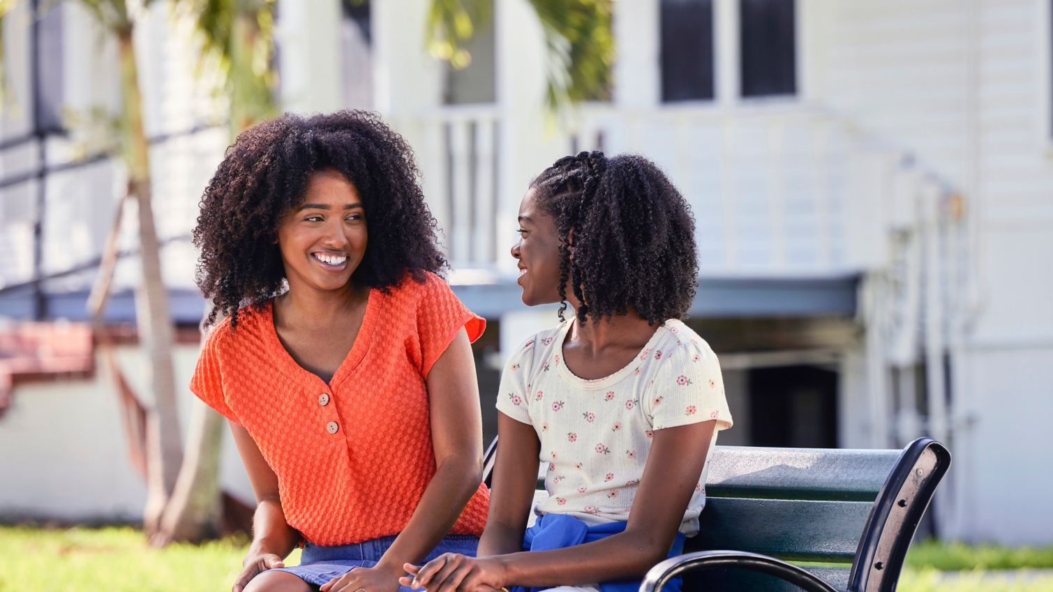 An adult sitting with a teen on a bench