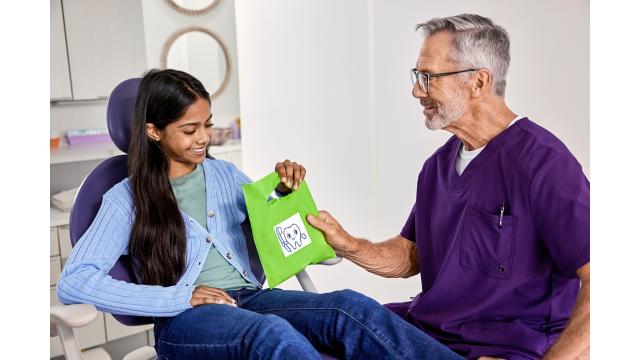 Teen receiving bag from dentist during exam