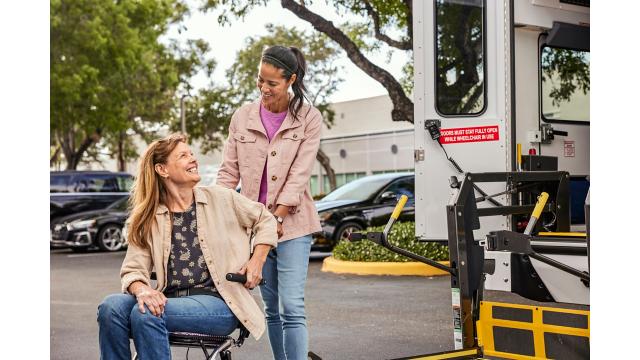 Woman in wheelchair and caregiver  getting on bus