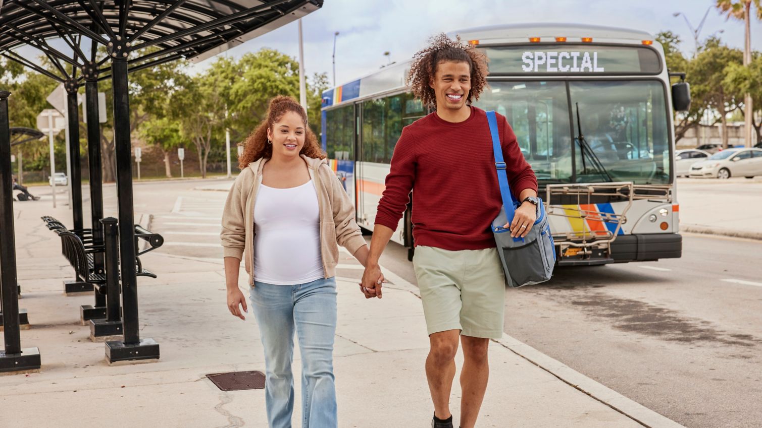 Two adults holding hands at a bus stop