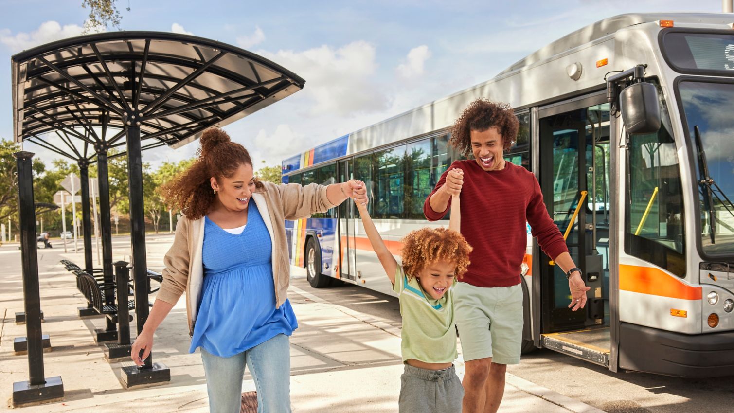 Two adults with a child at a bus stop