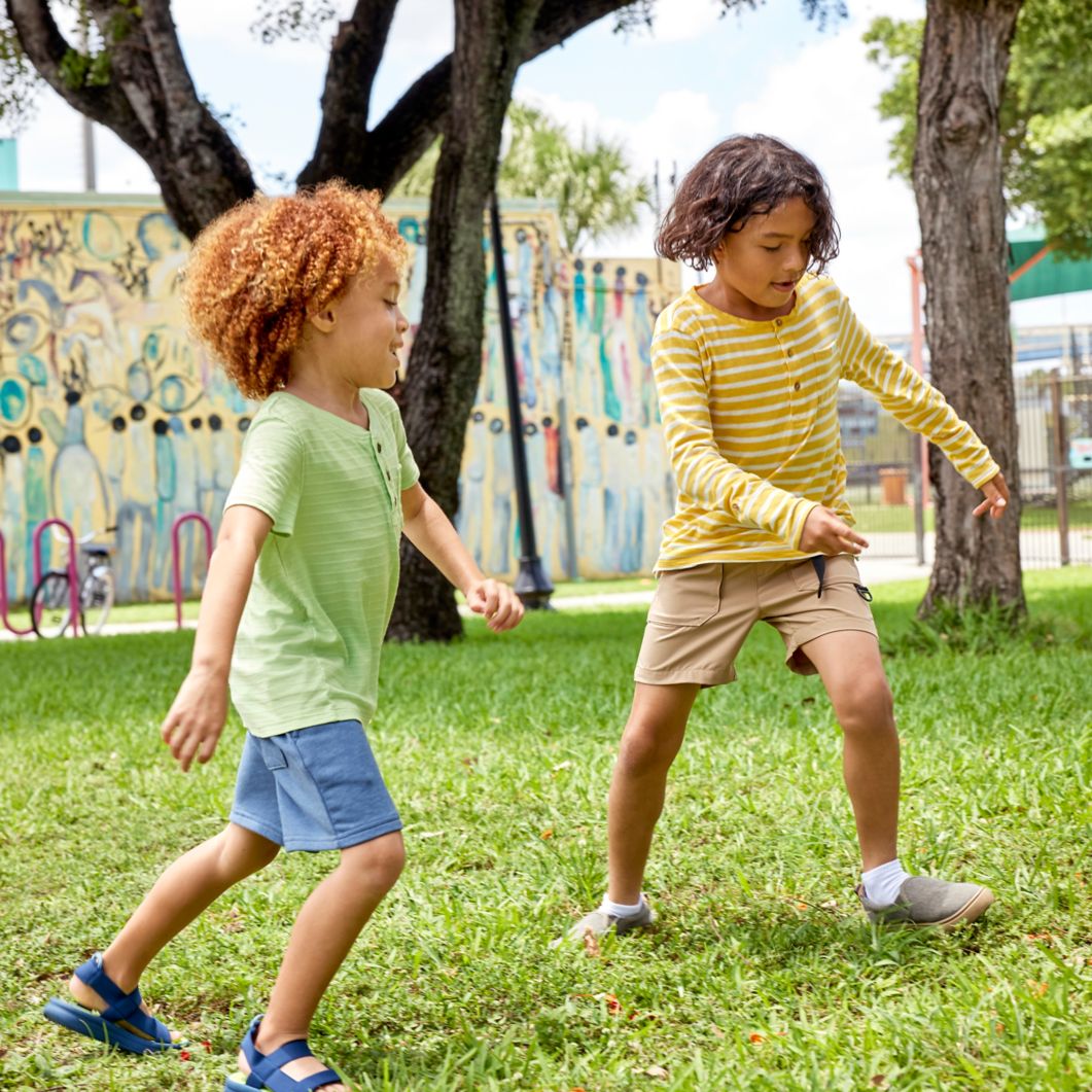 Two kids play soccer outdoors at a park