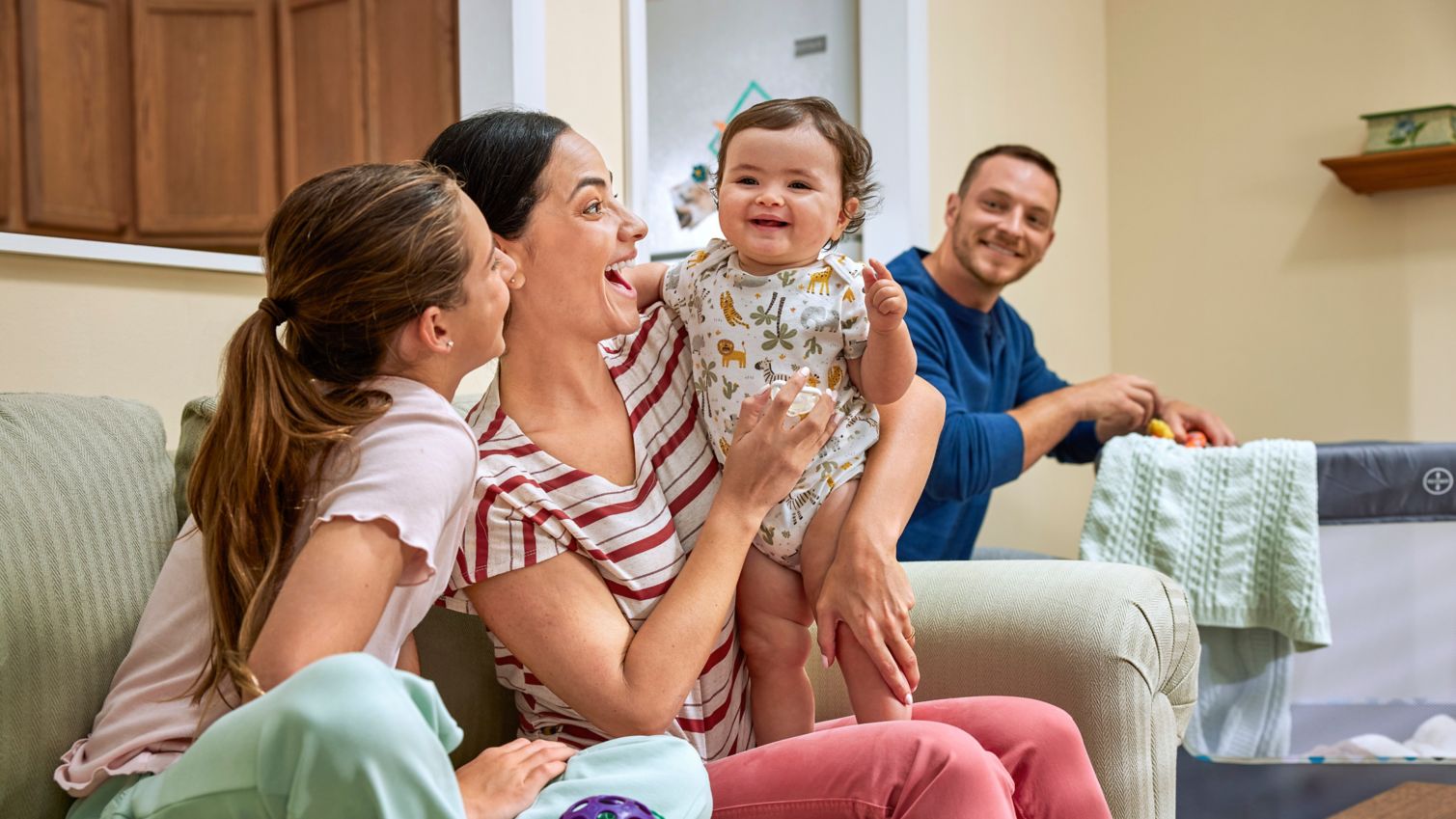 Parents and teen playing with infant.