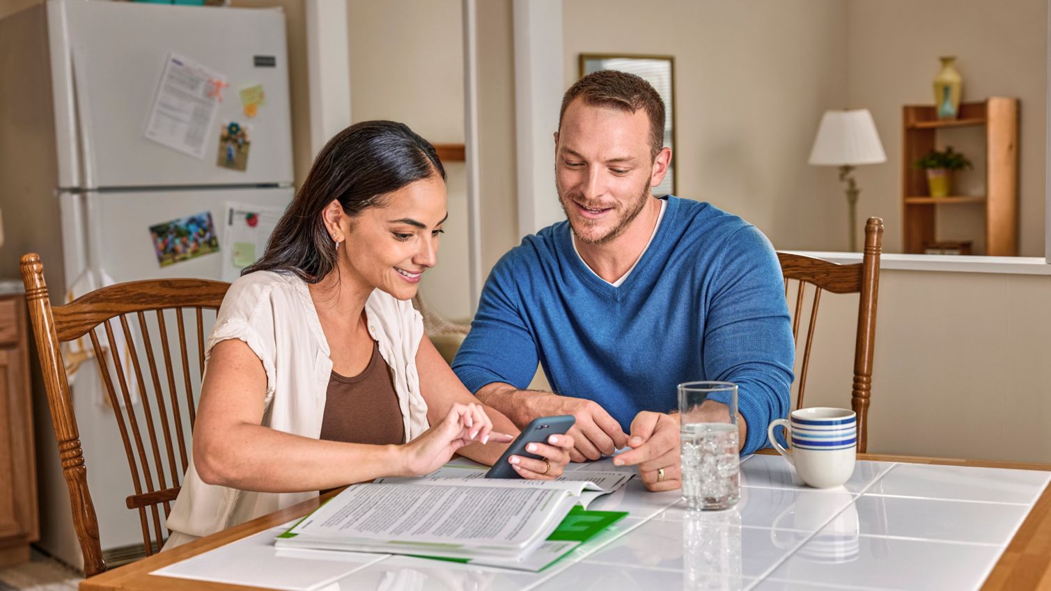 Two adults using a cell phone in their kitchen