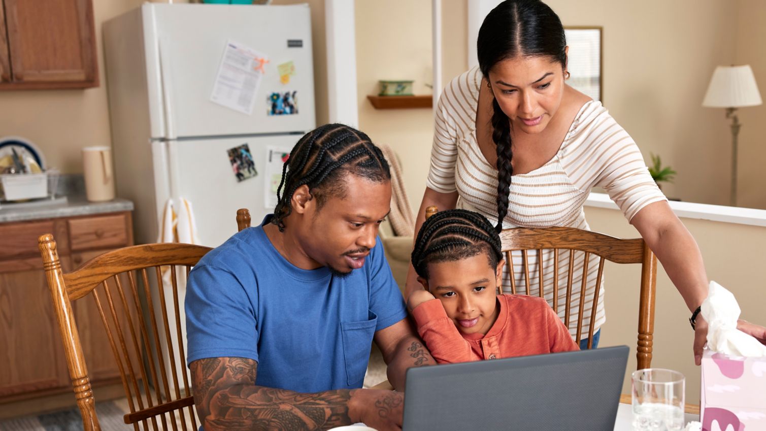 Family at kitchen table looking at computer screen
