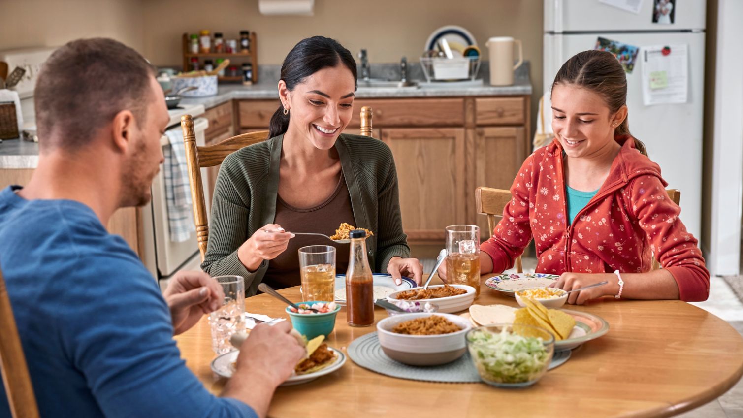 Two adults eating dinner with a child in a dining room