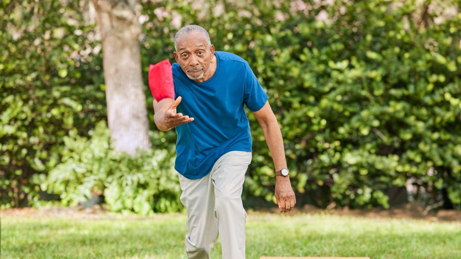 Senior Playing cornhole outdoors in yard.