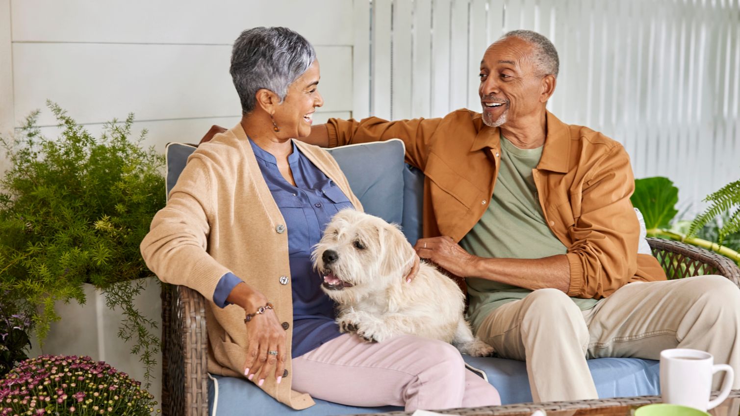 Two seniors sitting on a porch with a dog.