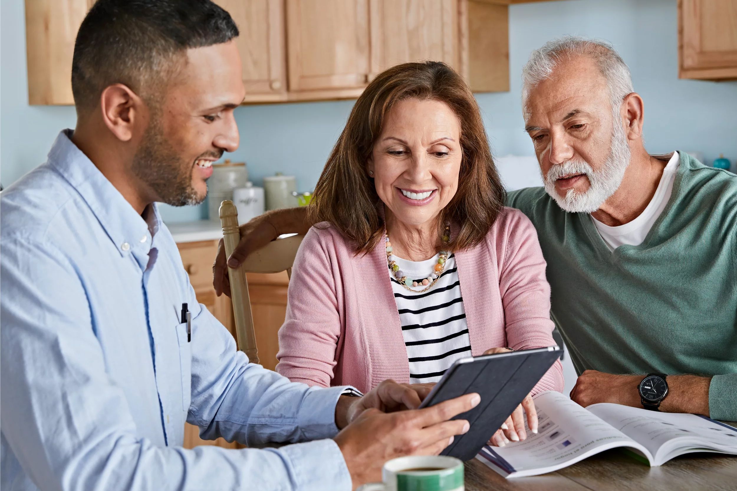 Agent sitting at table reviewing plan options on tablet wth senior couple