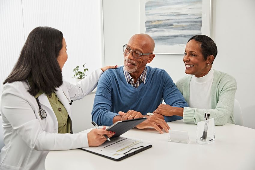 Woman doctor speaking with man and woman at a table.  