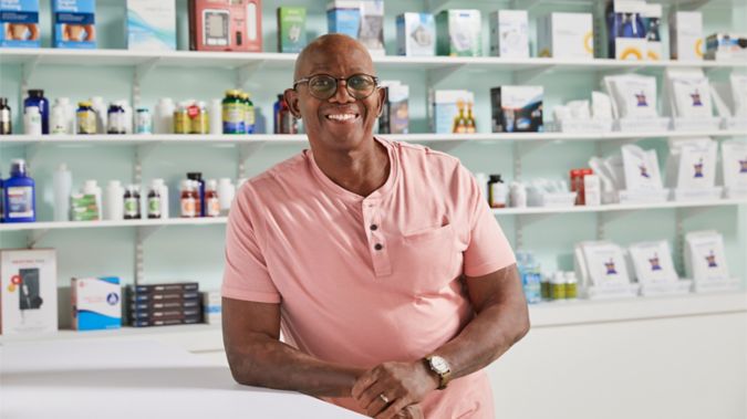 Man leaning on the pharmacy counter looking at camera