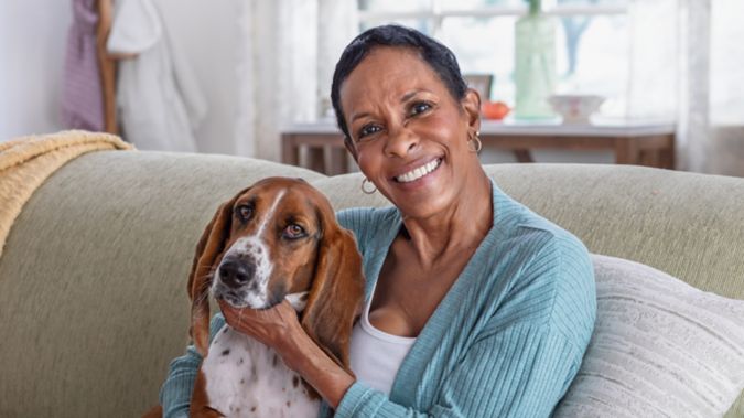 A retired lady sits with her dog on the couch