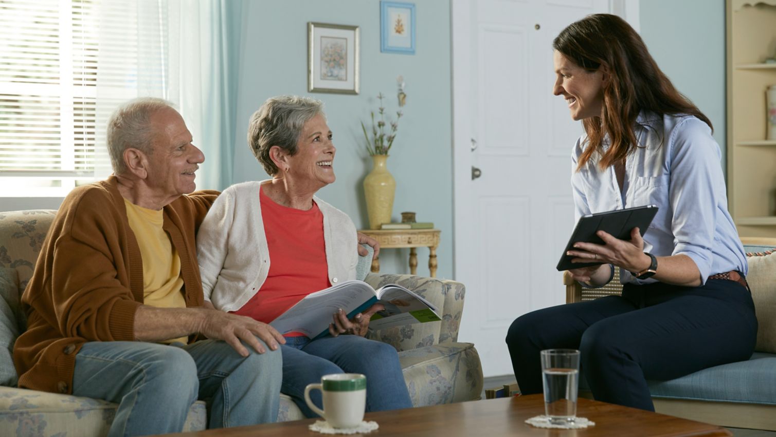 A lady talks to a retired couple in their living room
