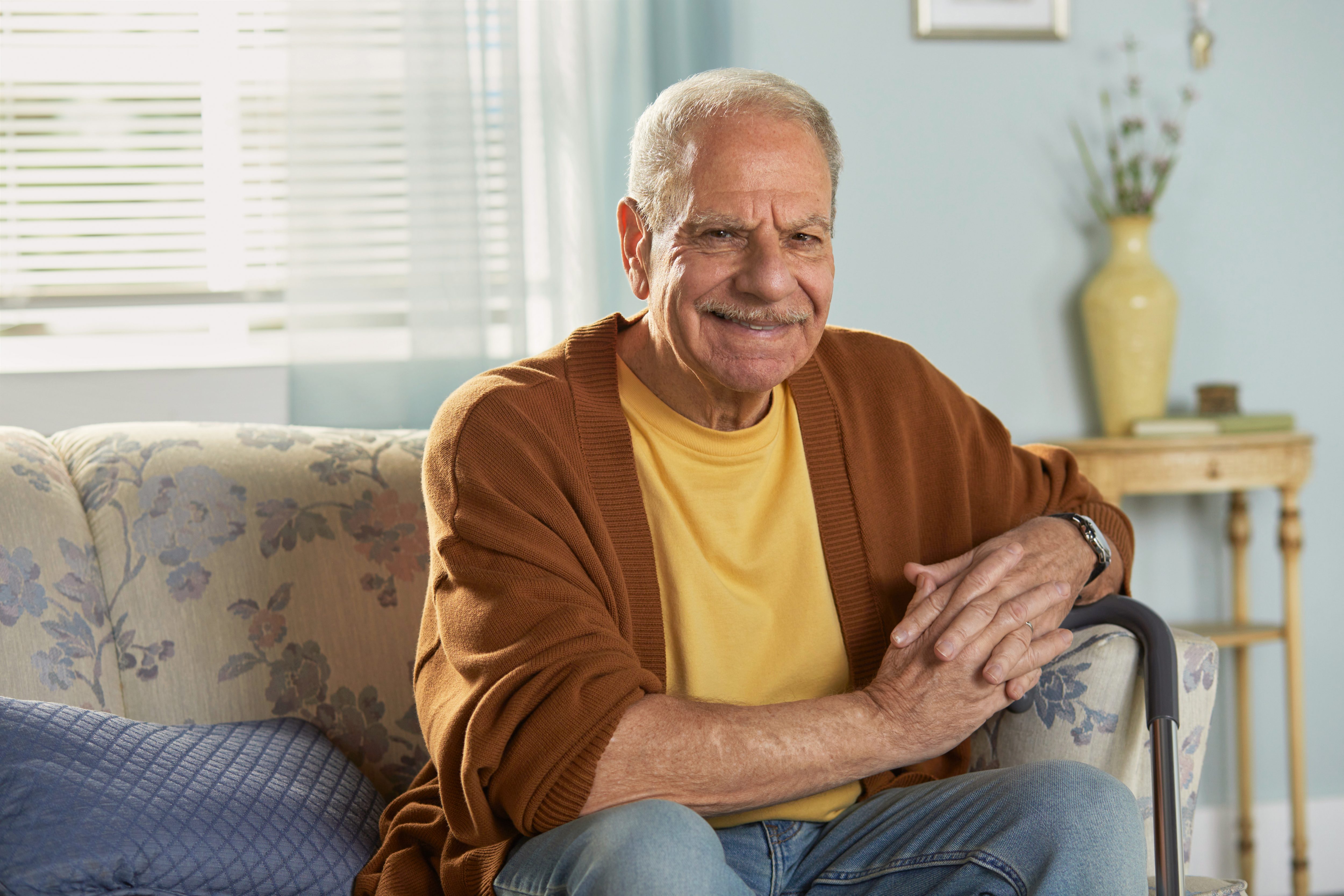 Portrait of smiling man sitting on couch with cane